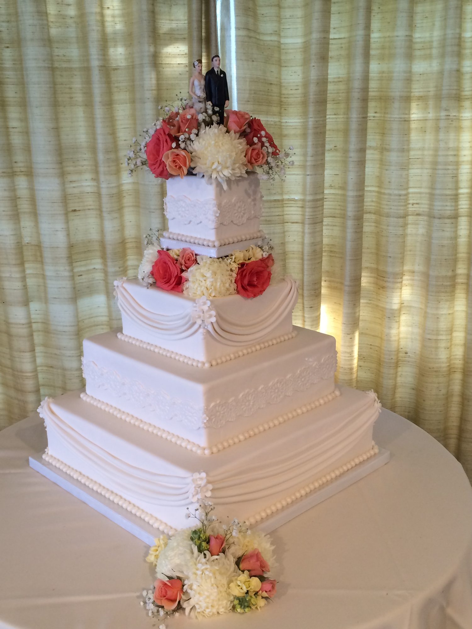 Square wedding cake with fondant drapes and flowers